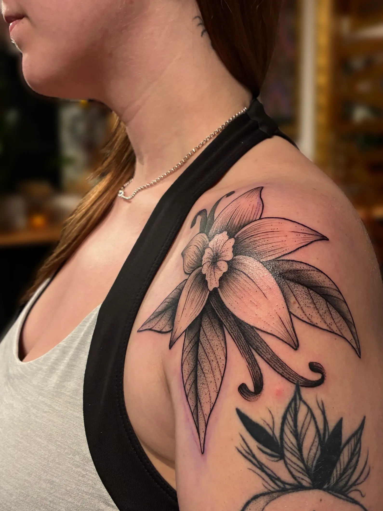 Grand tatouage floral noir et gris sur l'épaule