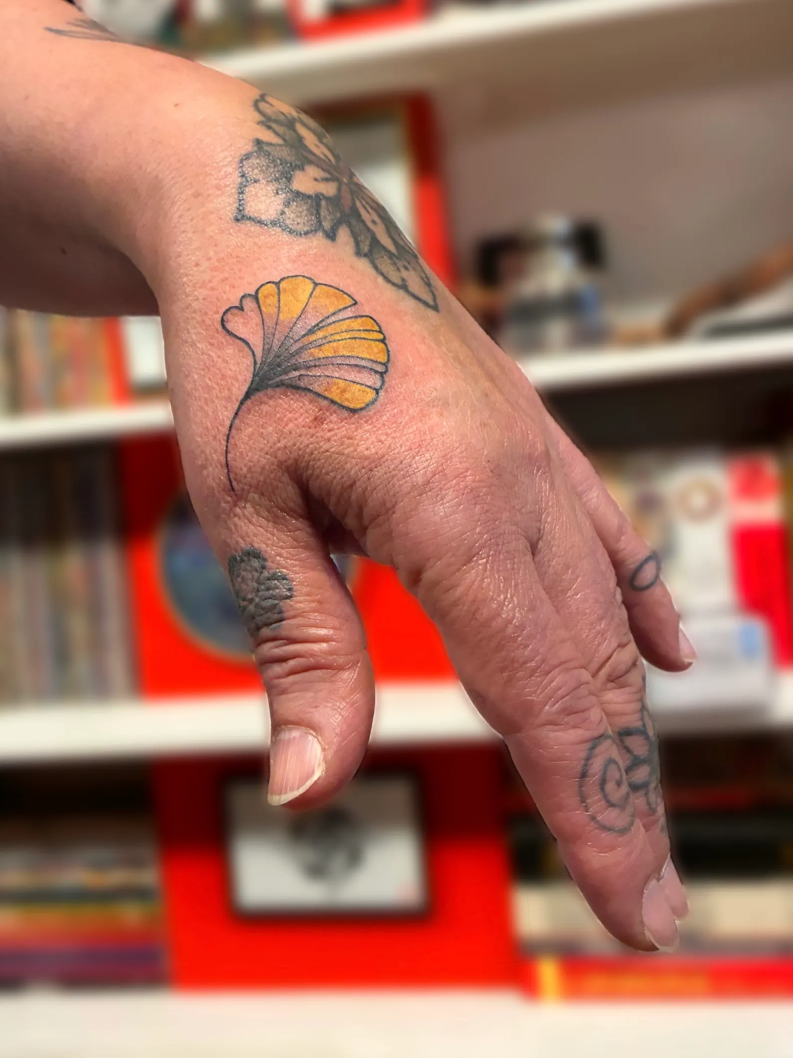 Petit tatouage coloré en forme de feuille de ginkgo sur la main