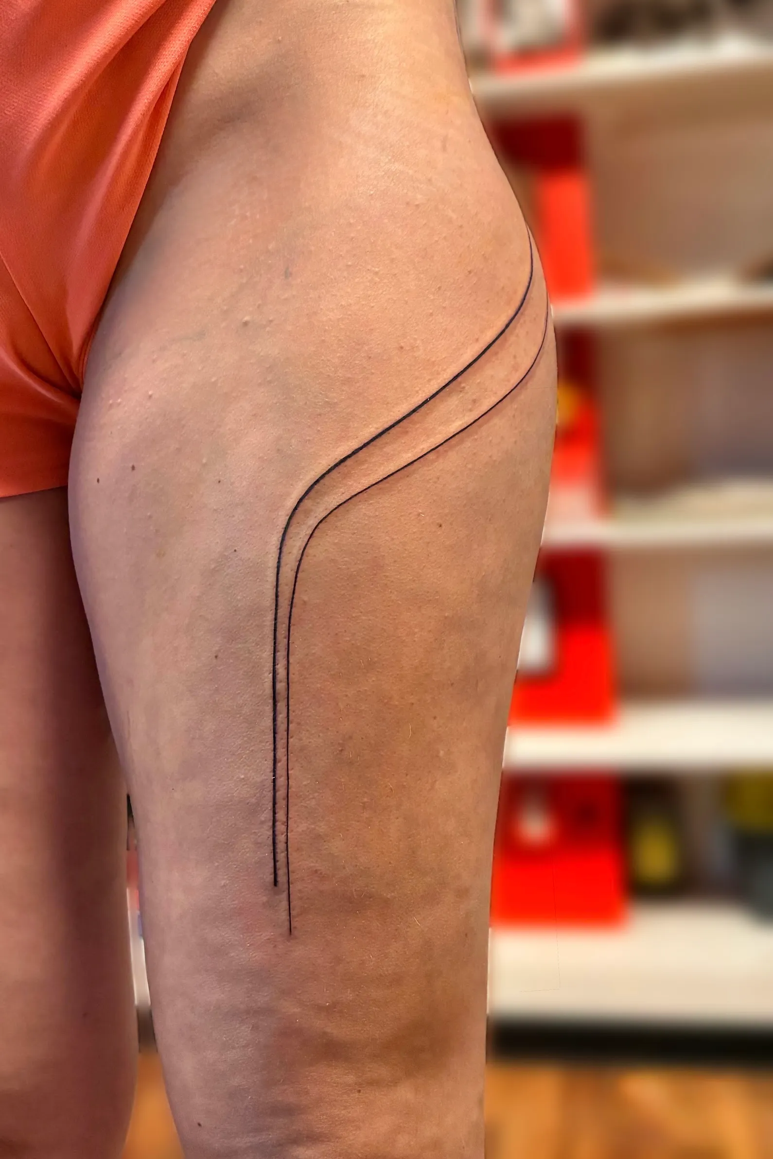 Tatouage minimaliste composé de deux lignes courbes sur le bras