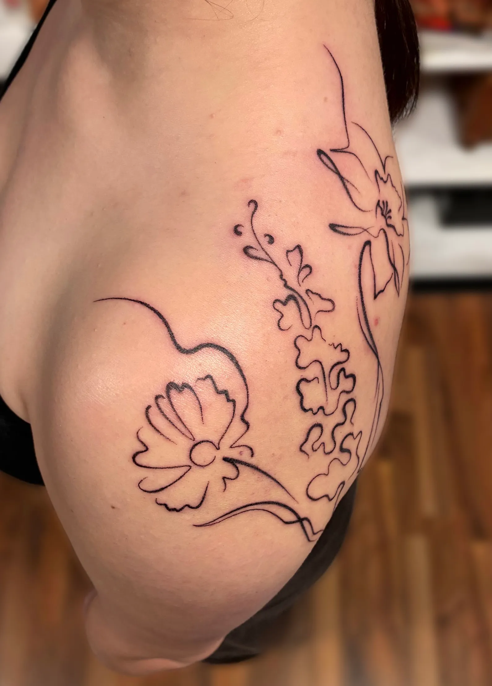 Tatouage floral en lignes fines sur la hanche