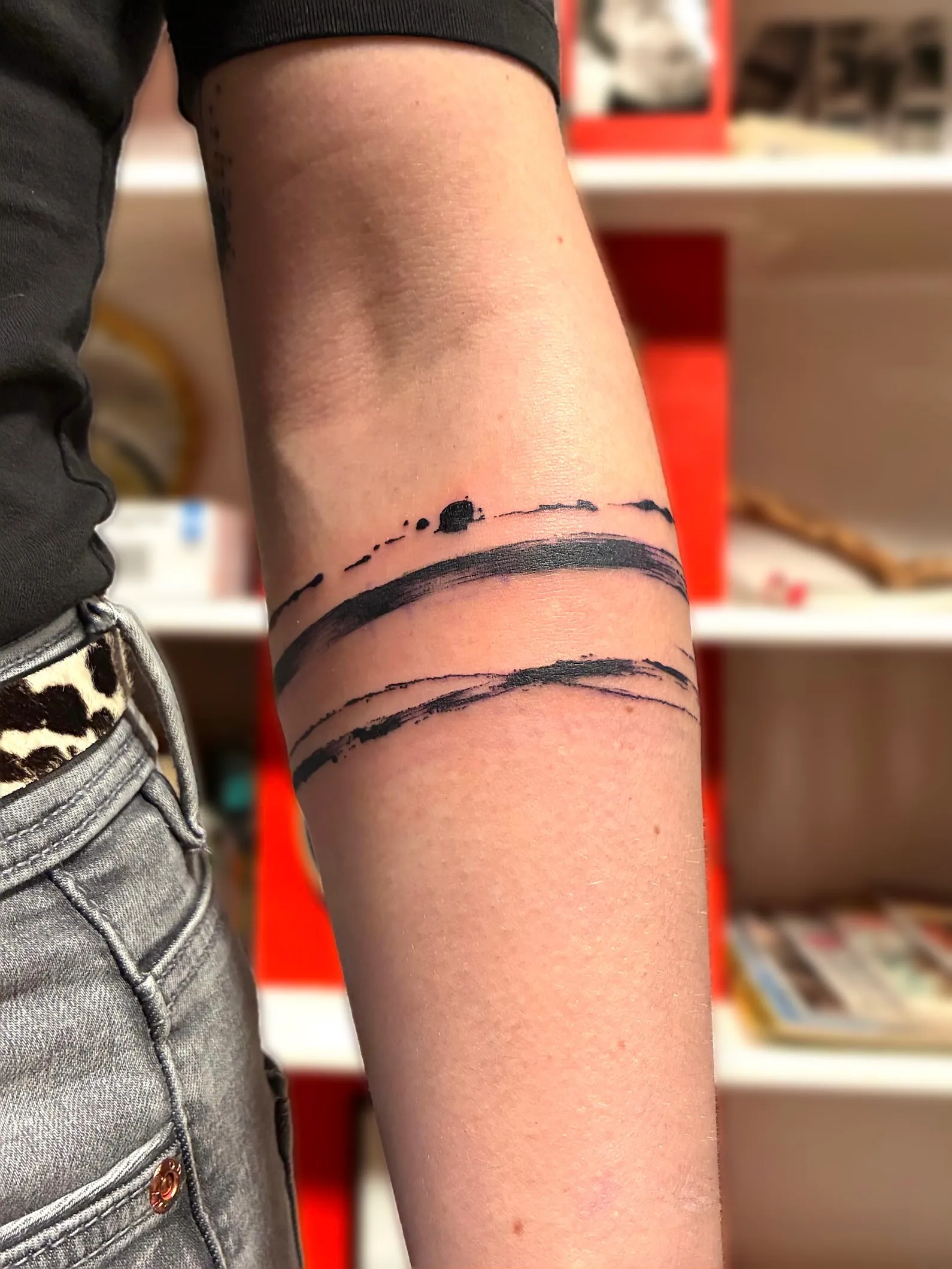 Tatouage abstrait en traits de pinceau noirs autour du bras