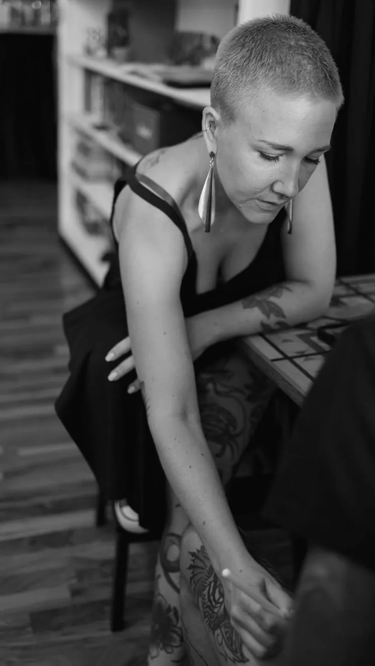 Kaiiza assise, penchée en avant, les coudes sur les genoux, à l'écoute pendant un rendez-vous au studio.