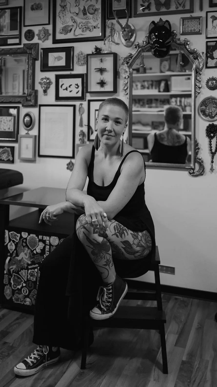 Portrait de Kaiiza, assise devant le mur de cadres de son studio