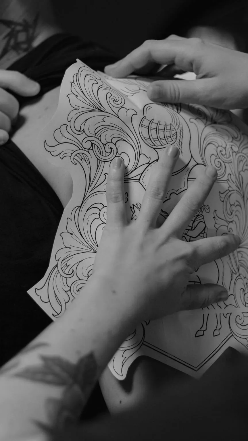 Mains tenant un dessin ornemental au trait sur papier, préparé avant la séance au studio