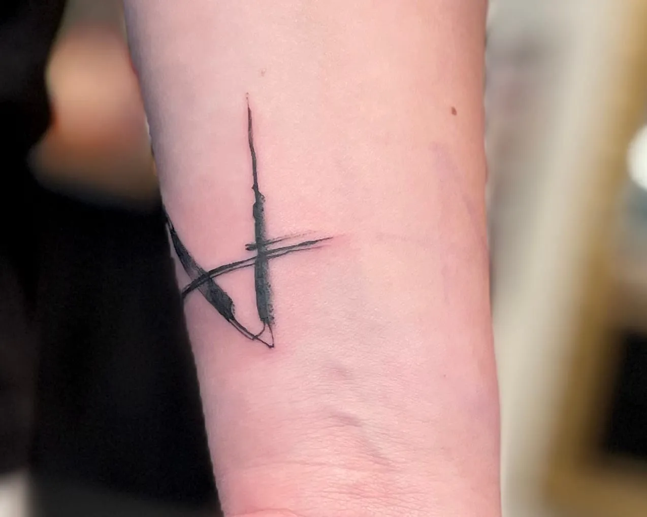 Tatouage abstrait forme de fins coups de pinceau noirs se croisant, sur le poignet