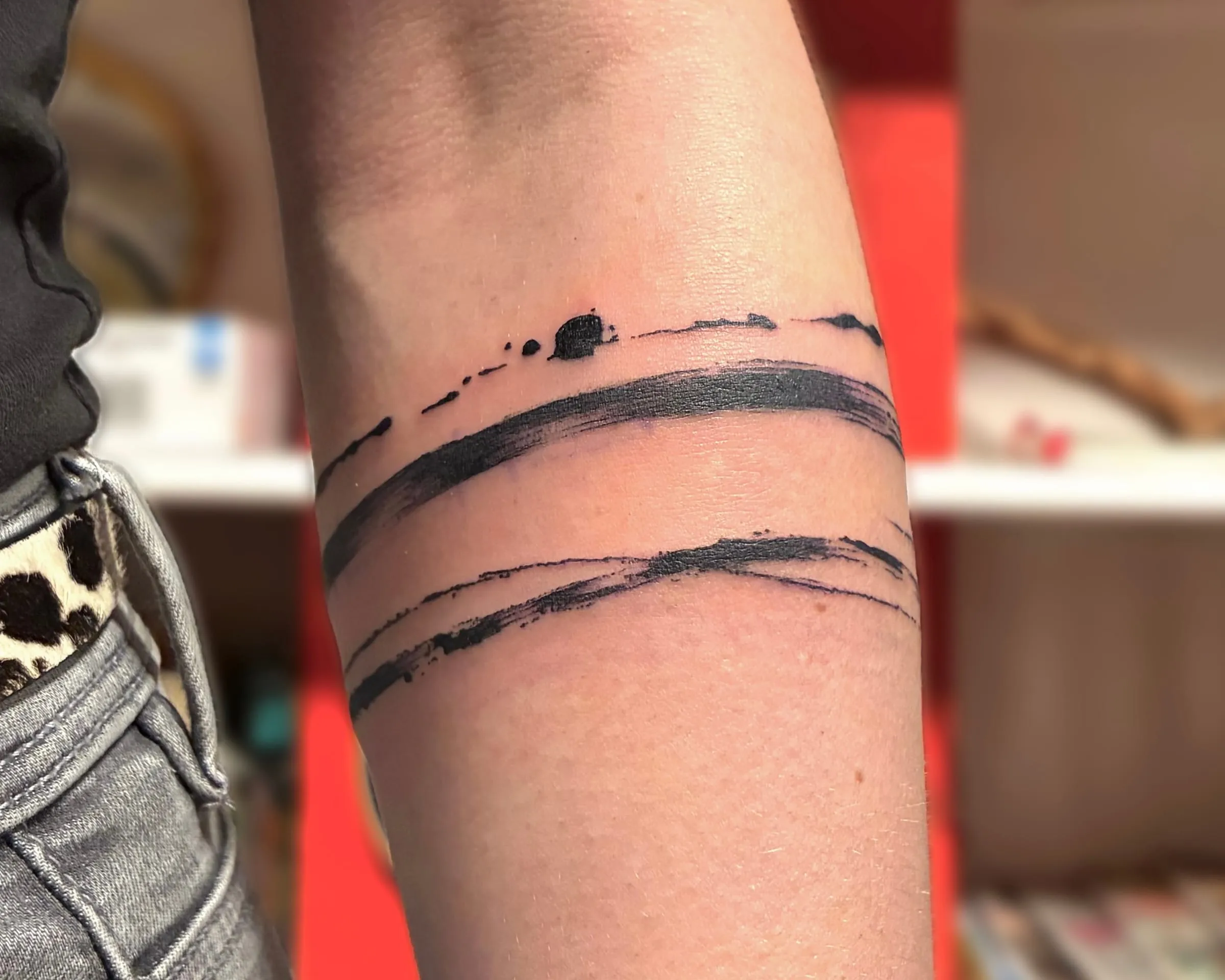 Tatouage abstrait de deux bandes en coups de pinceau noirs qui entourent l'avant-bras