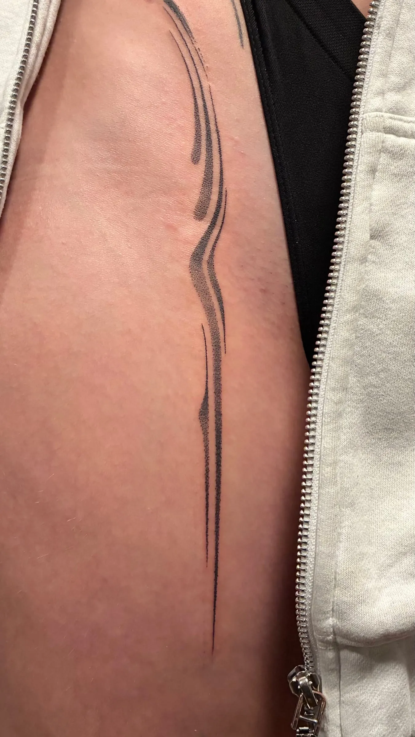 Tatouage abstrait de deux lignes noires fines et ondulantes le long de l'avant-bras