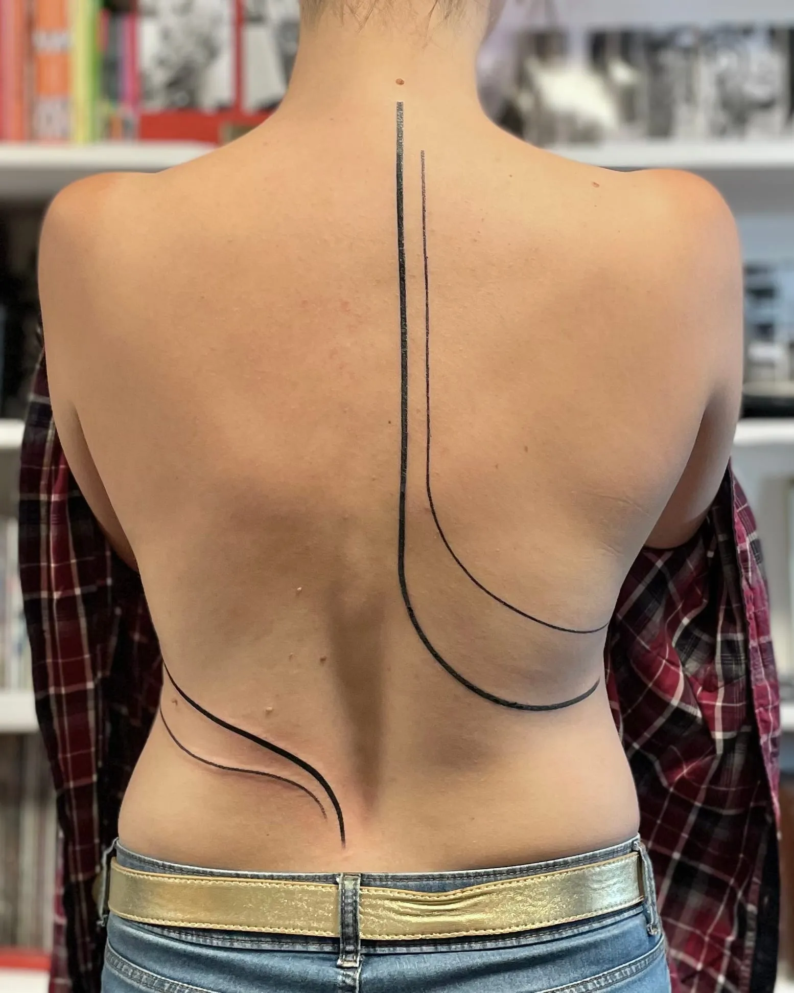 Tatouage abstrait de longues lignes noires courbes qui traversent le milieu du dos