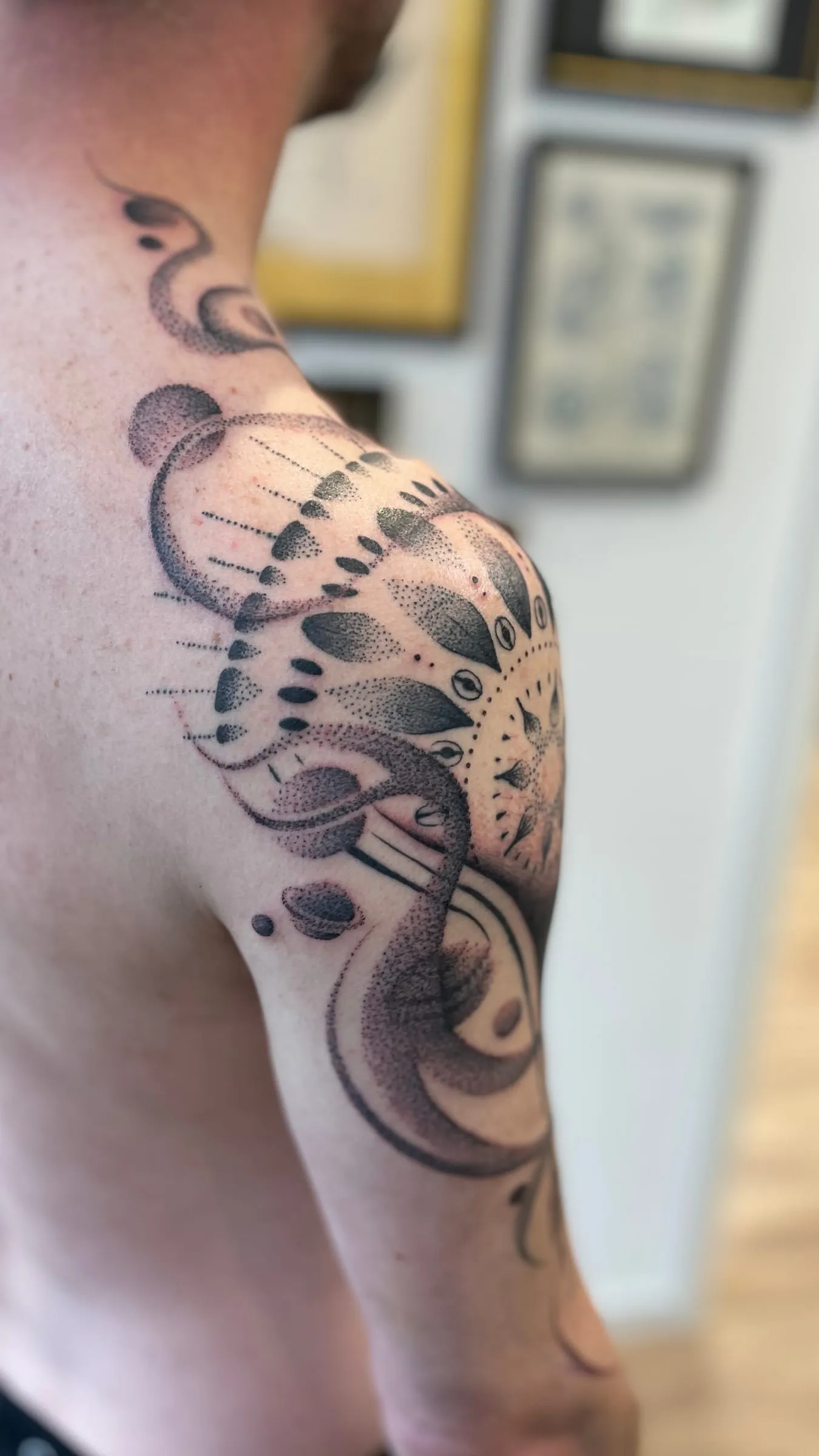 Tatouage abstrait en pointillés formant des volutes et des motifs organiques sur l'épaule